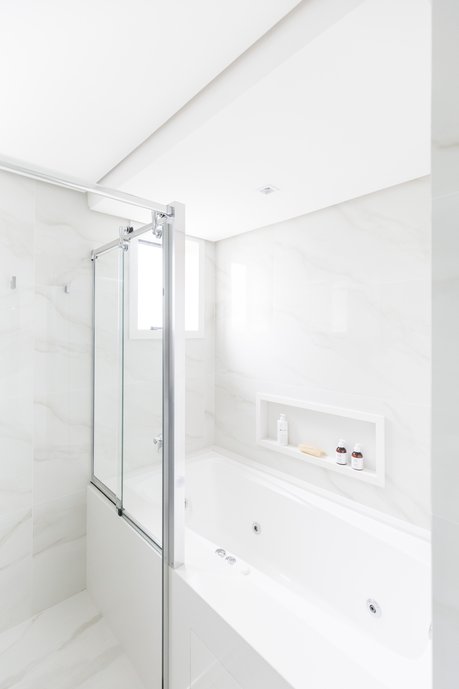Banho elegante do casal, com tons claros que conferem leveza visual ao ambiente. A banheira de hidromassagem com cromoterapia é o ponto alto do banho relaxante. Optamos por utilizar o mesmo revestimento no piso e nas paredes, pois tanto o cliente quanto nós, gostamos dessa unidade visual. Foto: Marcelo Donadussi