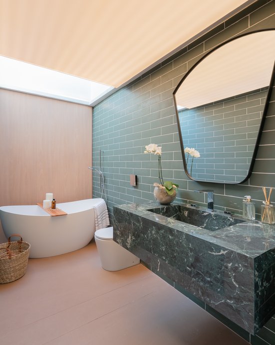 Banheiro que explora os tons verdes, sendo nas paredes como bancada com cuba moldada em terralma mandacatu.