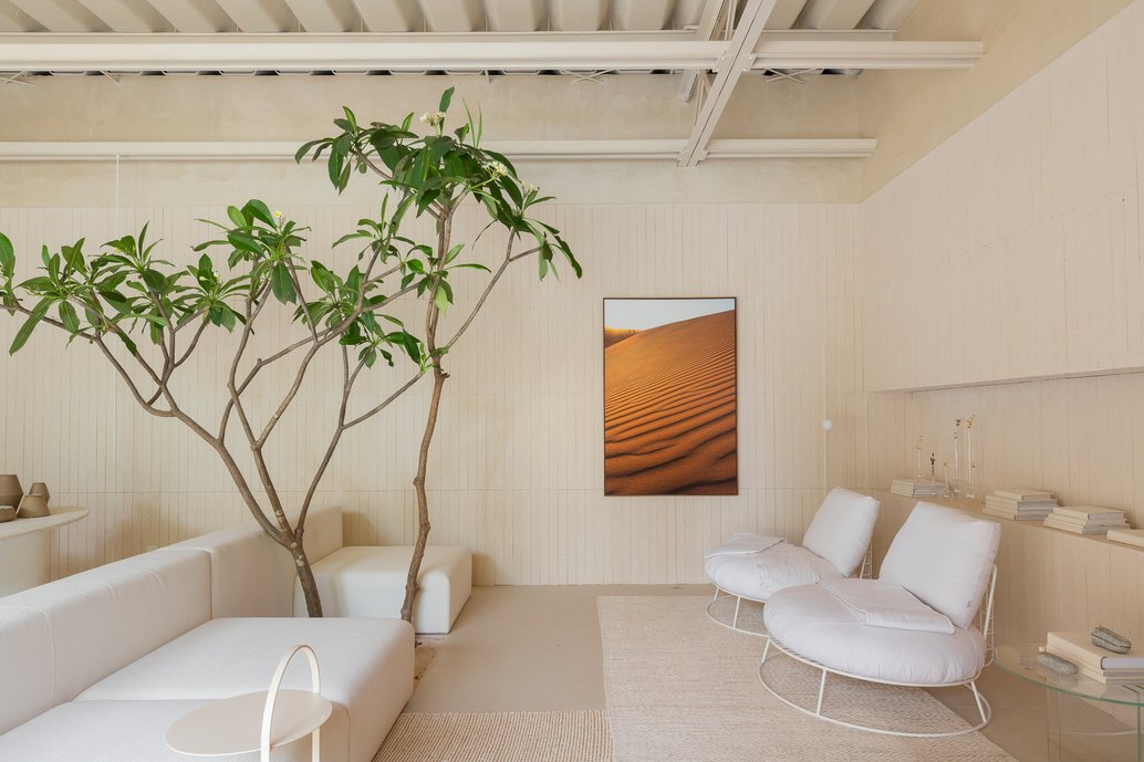 Sala de estar com sofá modular com uma árvore incorporada, poltronas, mesas de apoio. Paredes e nicho com tijolinho Chelsea Off White e o porcelanato de grande formato Dansk no piso.