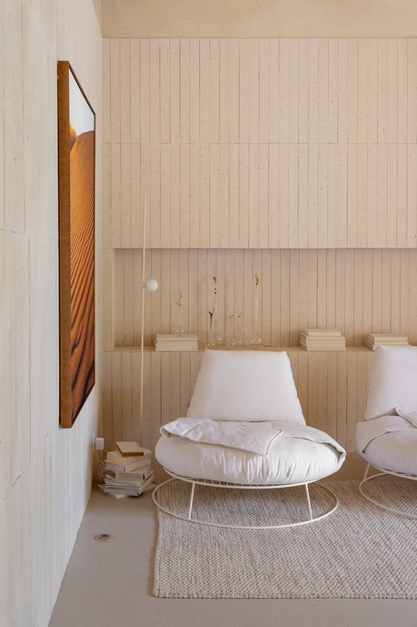 Poltronas, luminárias e obras de arte da sala de estar. Paredes e nicho com tijolinho Chelsea Off White e o porcelanato de grande formato Dansk no piso.