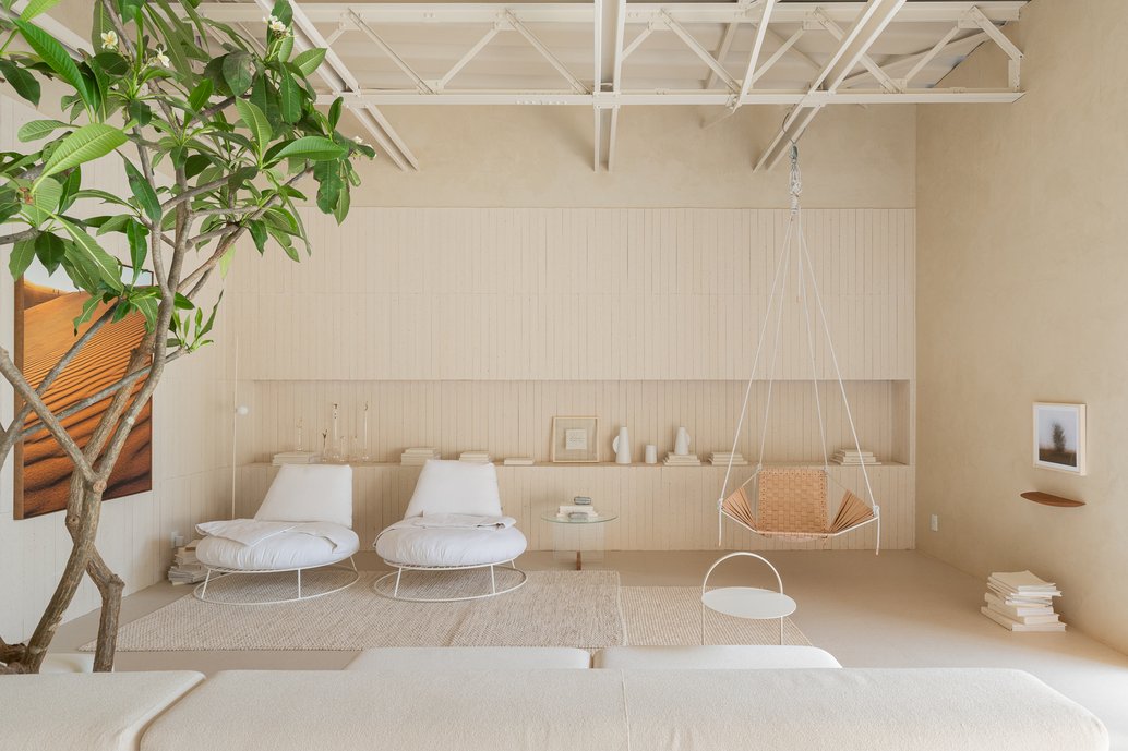 Sala de estar com sofá modular com uma árvore incorporada, poltronas, mesas de apoio. Paredes e nicho com tijolinho Chelsea Off White e o porcelanato de grande formato Dansk no piso.